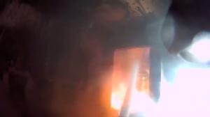Firefighter with helmet cam putting out house fire